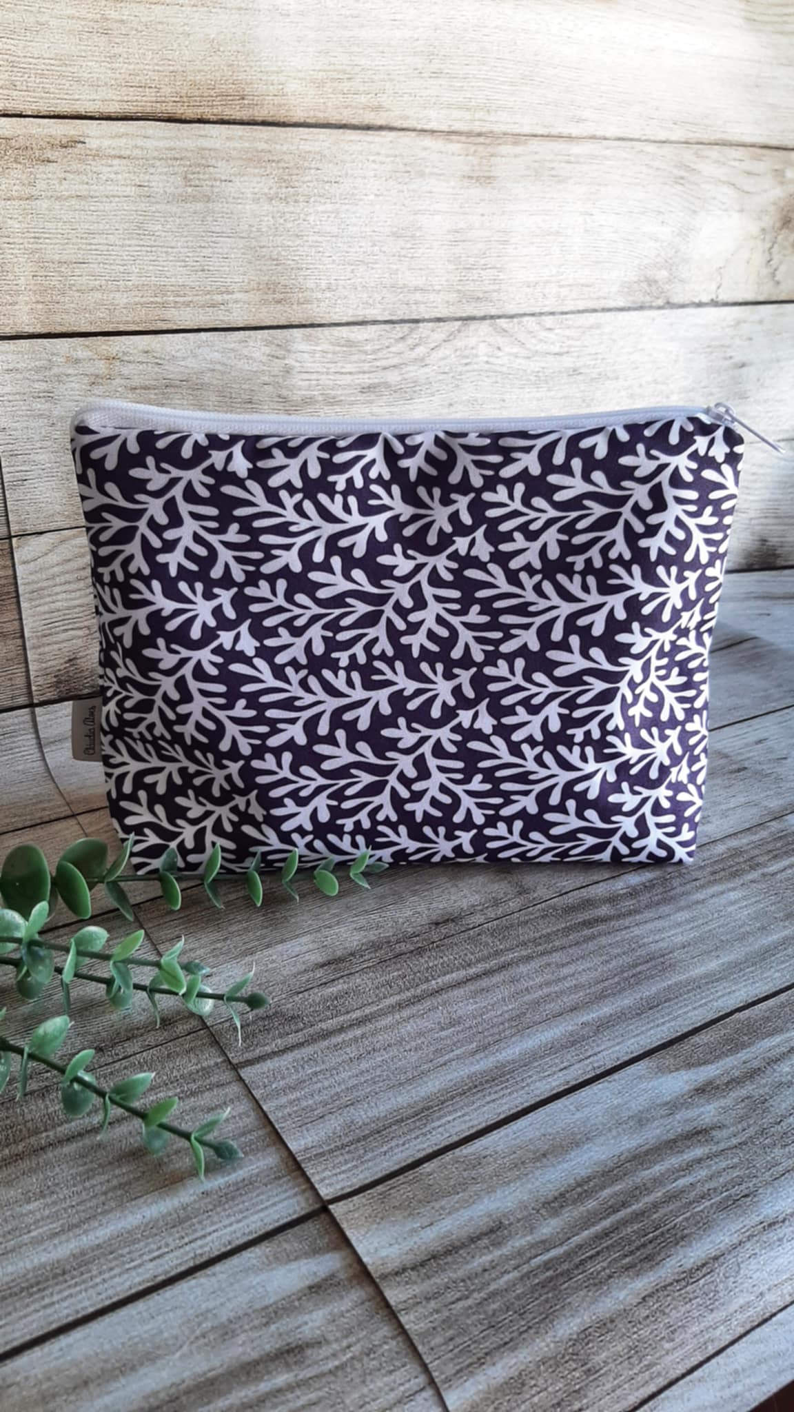 Necessaire tradicional grande em Nylon estampado, perfeita para viagens ou dias de praia. Tamanho grande. Abertura ampla com fecho de correr. Com dimensões de 26x18 cm, este necessaire tradicional combina estilo e praticidade com seu elegante padrão de Corais brancos com fundo preto.